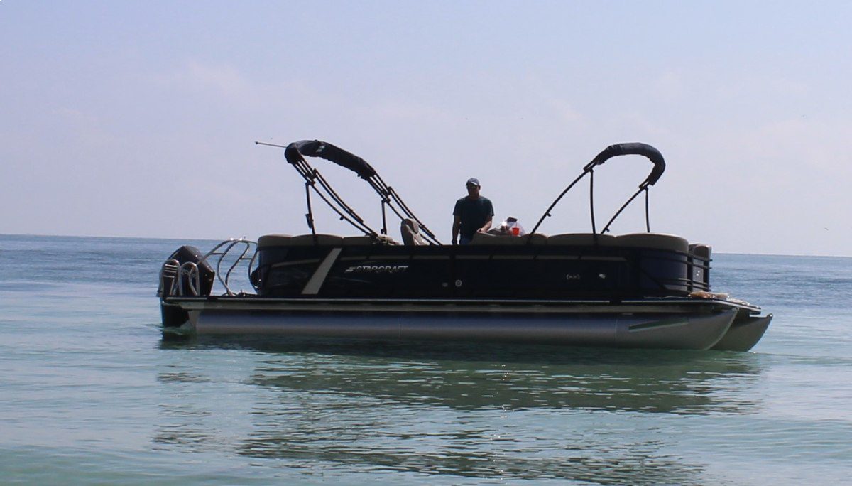 A man in black shirt riding on top of boat.